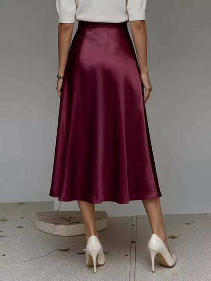 Person wearing a burgundy satin skirt with a plain background