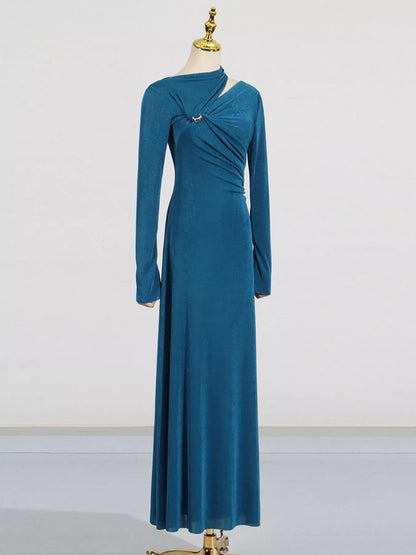 A long-sleeve teal blue maxi dress with a draped crossover front detail and a small silver-toned embellishment, displayed on a mannequin against a plain light gray studio background.