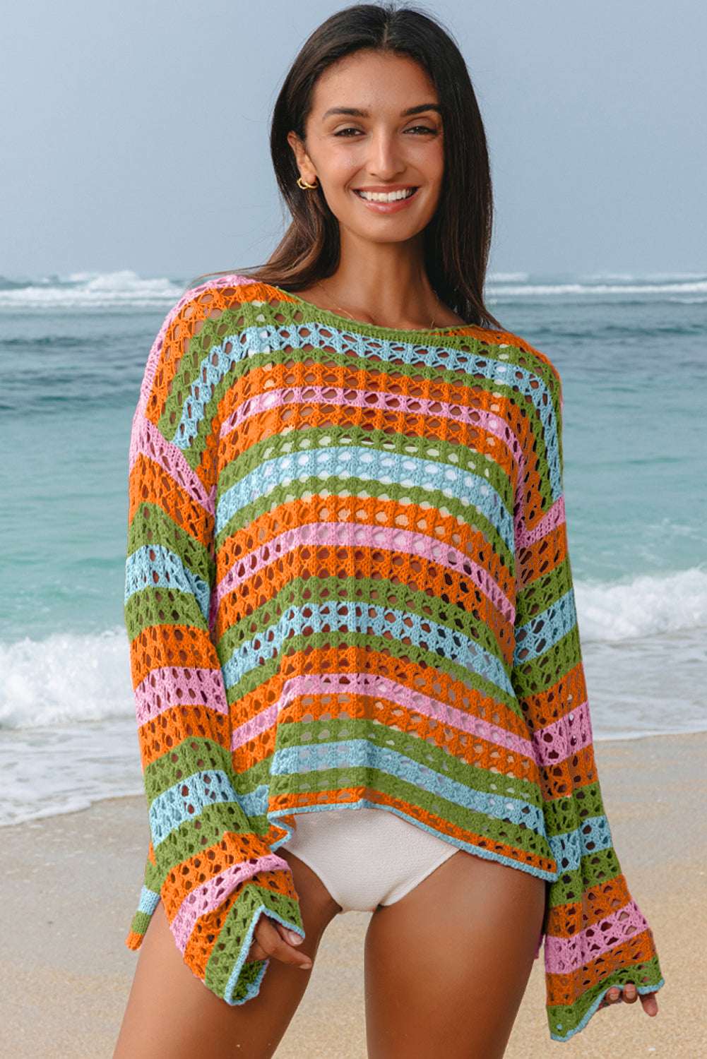 Woman wears a multi-colored striped crochet open knit sweater with orange, green, blue, and pink horizontal bands.