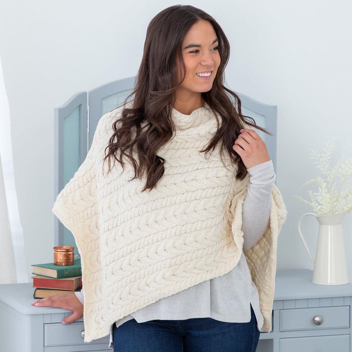 Woman wearing a cream-colored poncho in a home setting