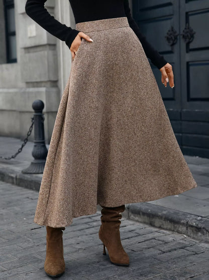 Person wearing a brown skirt and brown boots on a city street.
