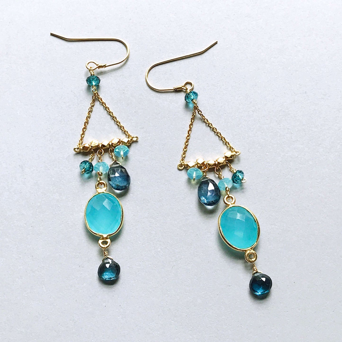 Pair of gold earrings with blue gemstones on a white background