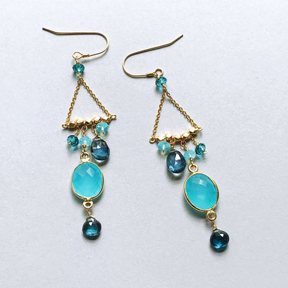 Pair of gold earrings with blue gemstones on a white background