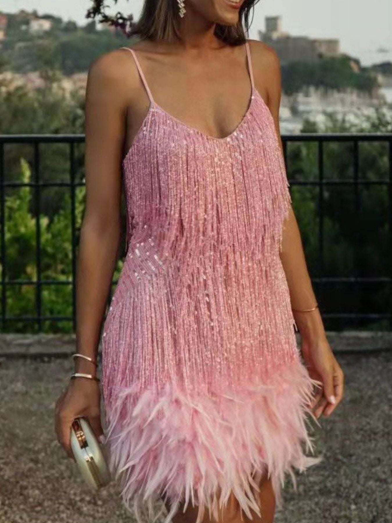 Woman wearing a pink feathered dress with a blurred outdoor background