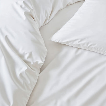 Close-up of a white comforter and pillow on a light background