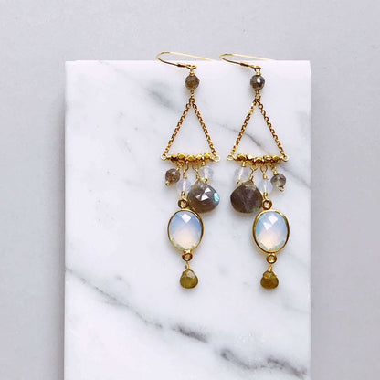 Pair of gold earrings with gemstones on a marble surface