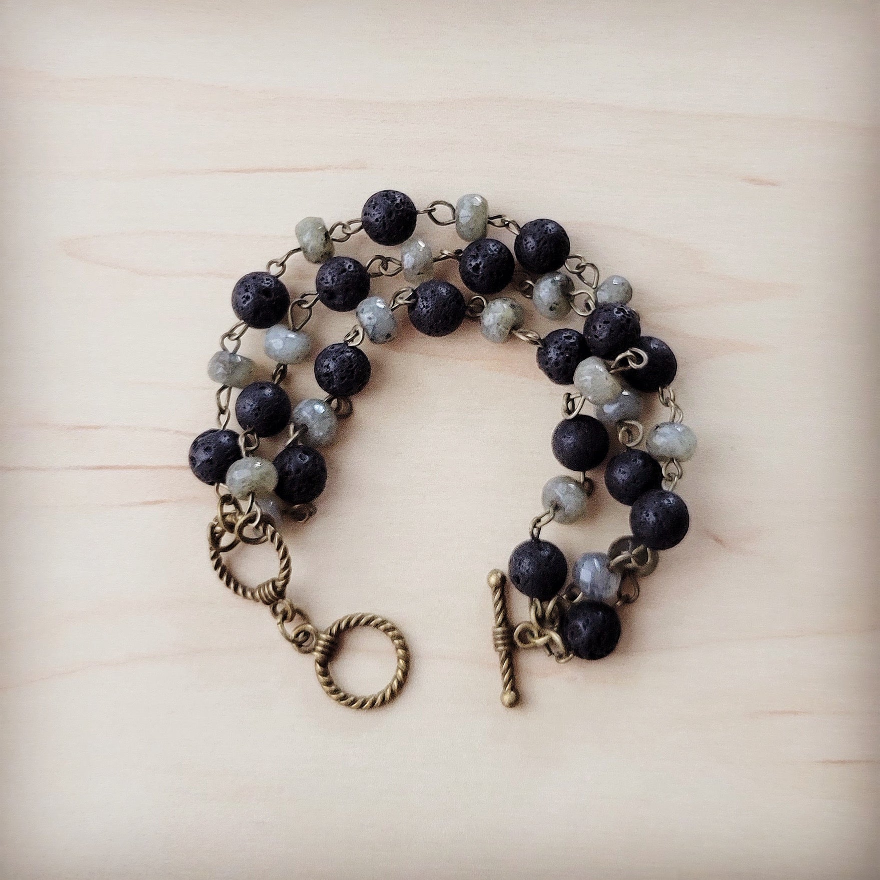 Bracelet with black and gray beads on a light wooden surface