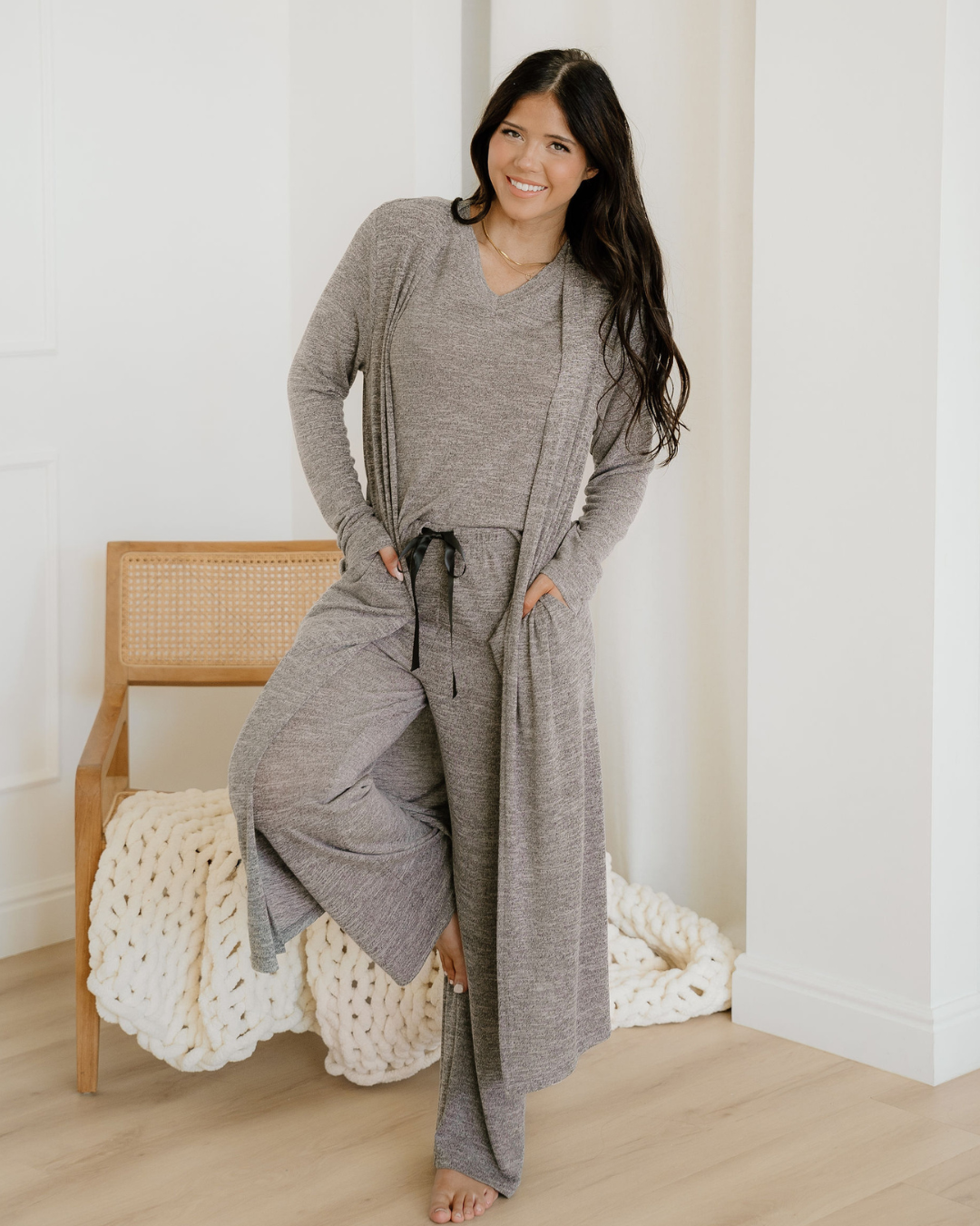 Woman wearing a gray loungewear set in a minimalistic room.