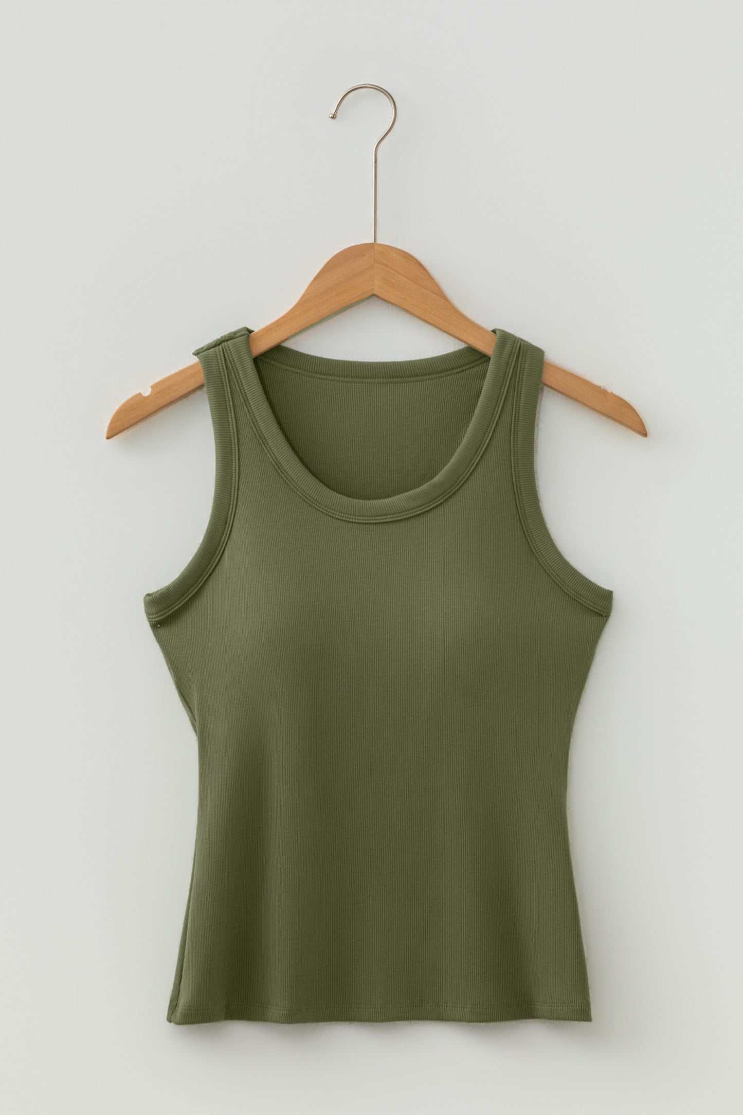 Green tank top on a wooden hanger against a white background