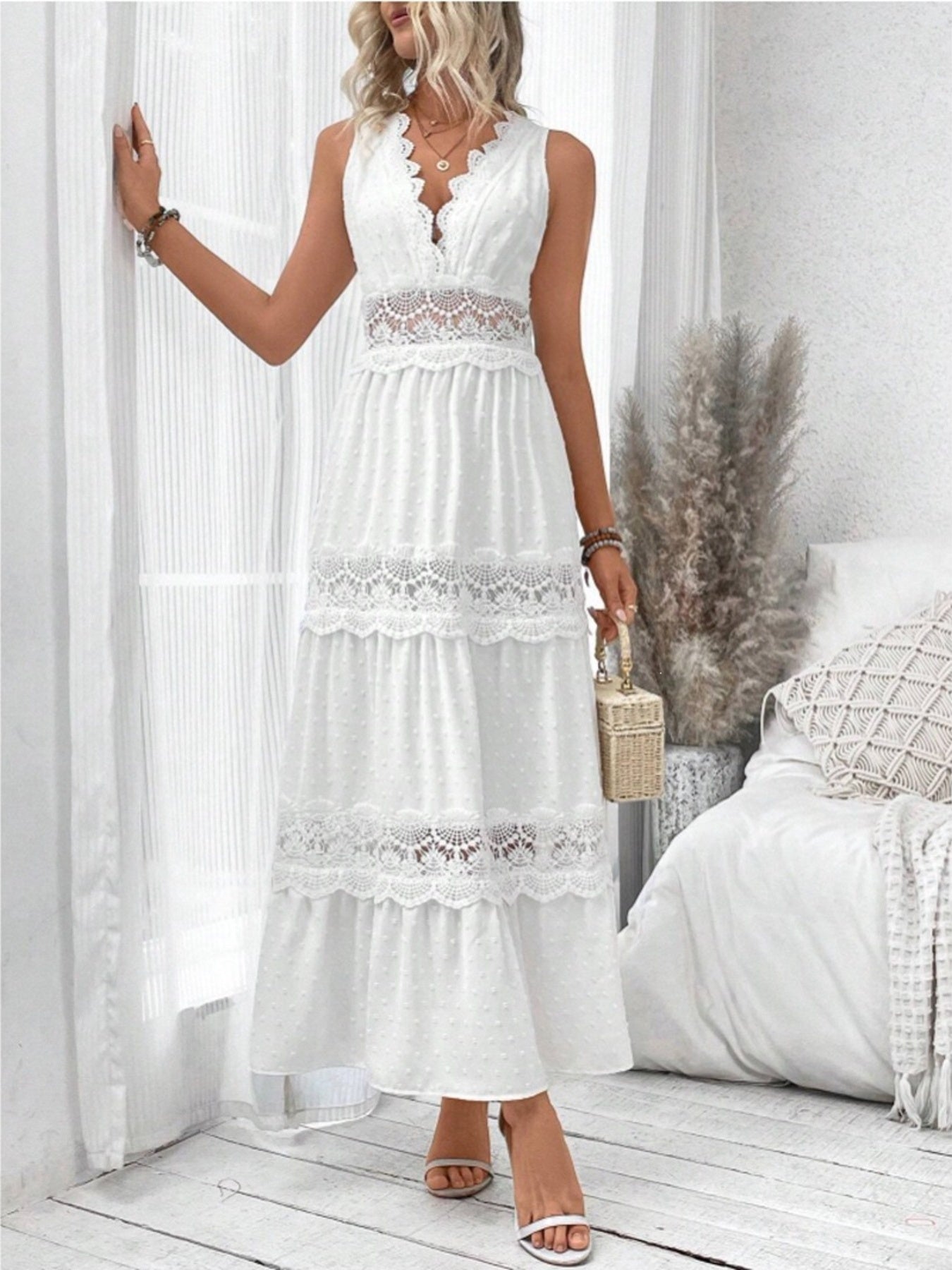 Woman wearing a white lace dress in a bright room with white walls and wooden floor.