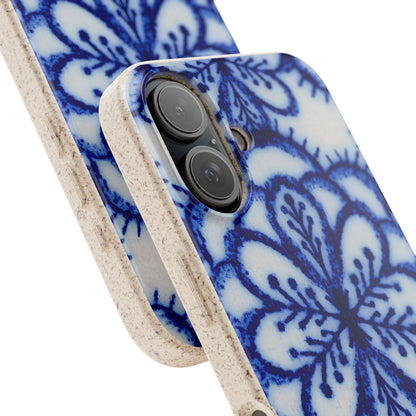 A close-up of a smartphone case with a blue floral or mandala-style pattern on a white background, featuring a textured beige edge and bumper around the camera cutout.