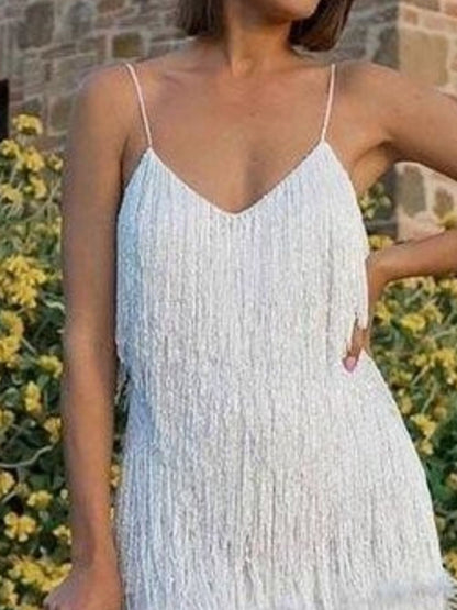 Woman wearing a white lace dress with a blurred background of greenery and a stone wall.