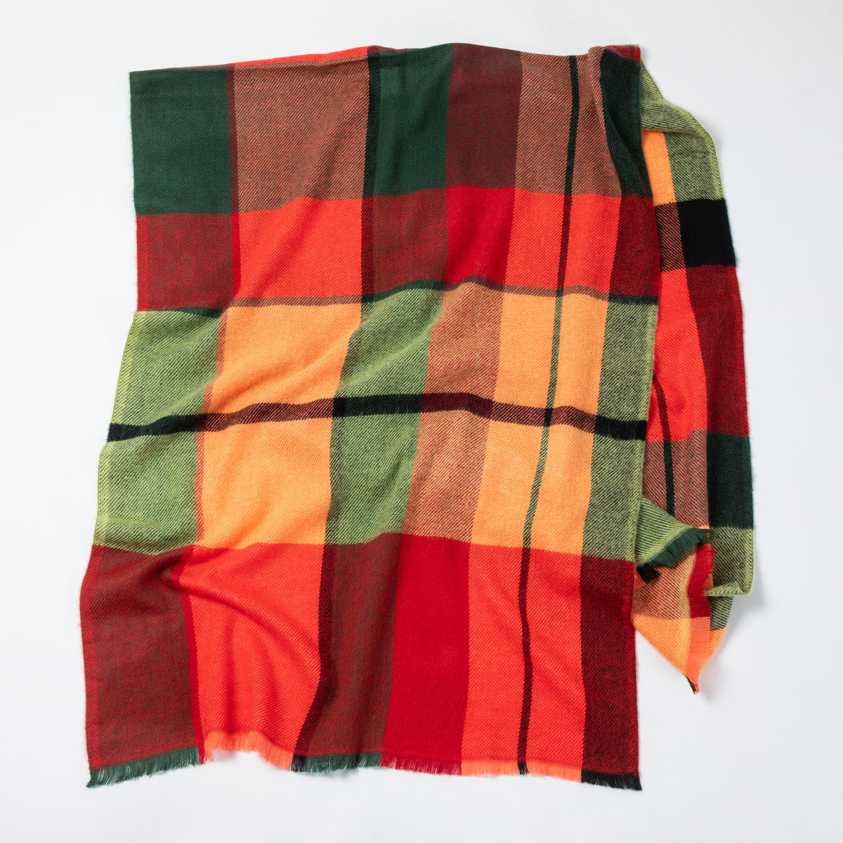 Plaid blanket with red, green, and orange colors on a white background