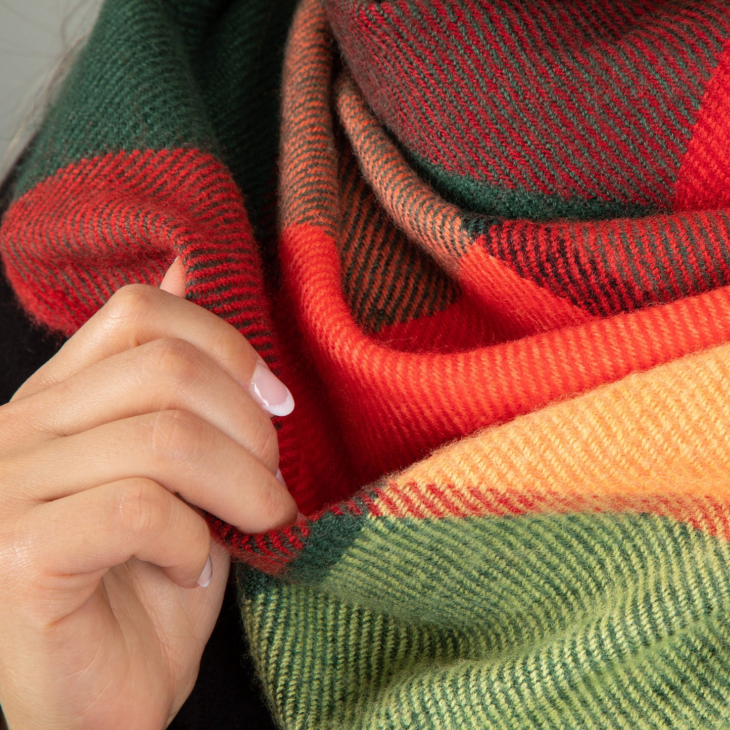 Colorful striped fabric with a hand holding it, featuring red, green, and orange.
