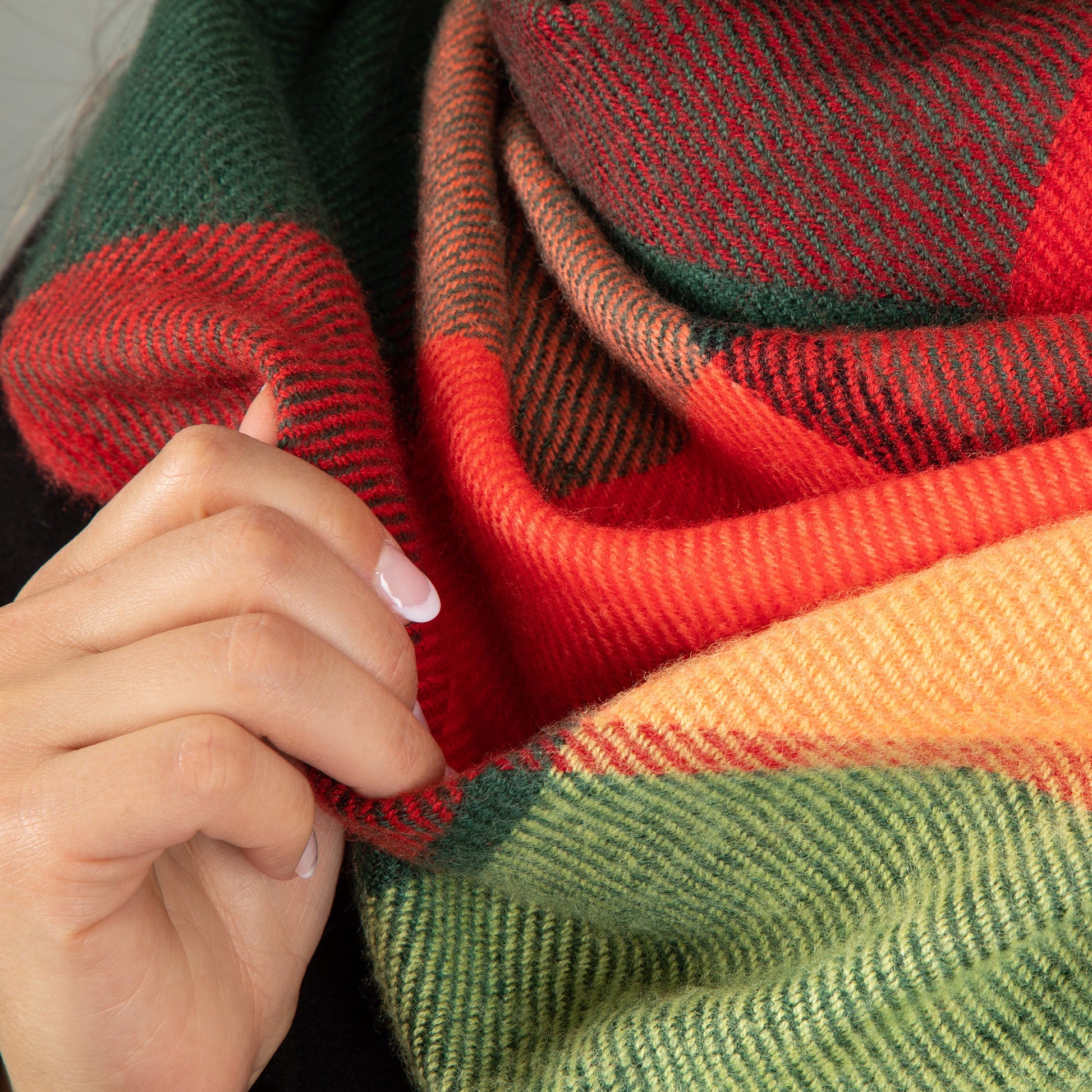Colorful striped fabric with a hand holding it, featuring red, green, and orange.