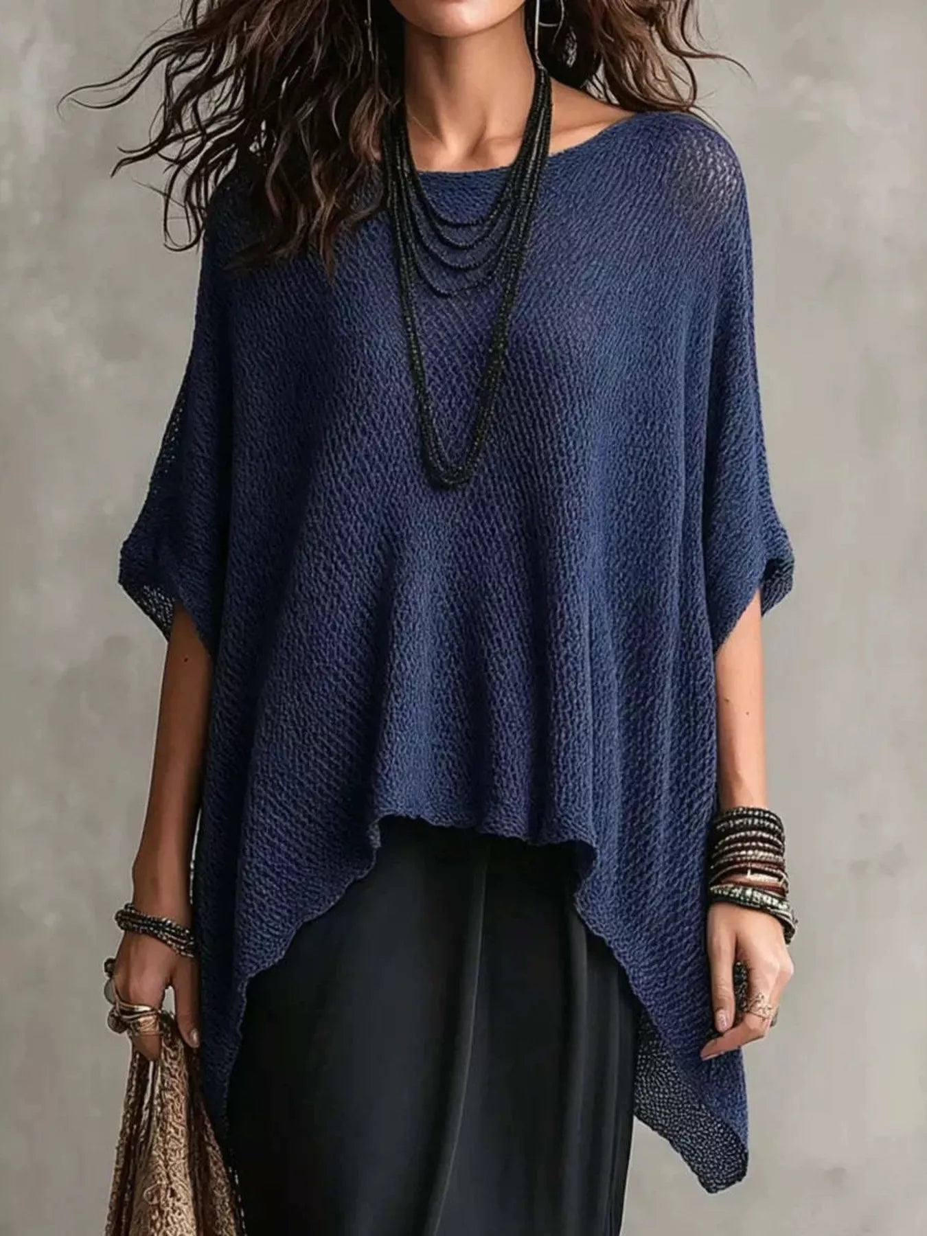 Woman wearing a blue knitted poncho against a gray background