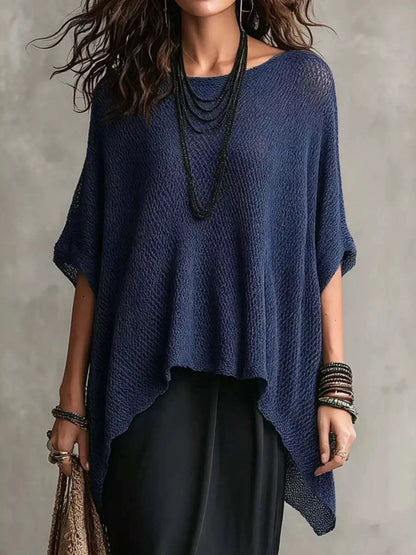 Woman wearing a blue knitted poncho against a gray background