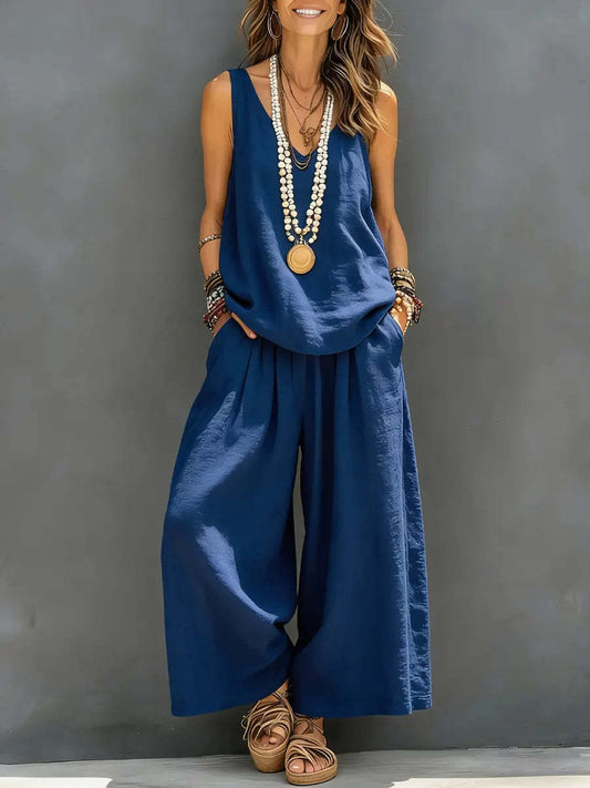 Woman wearing a blue jumpsuit with wide-leg pants against a gray background