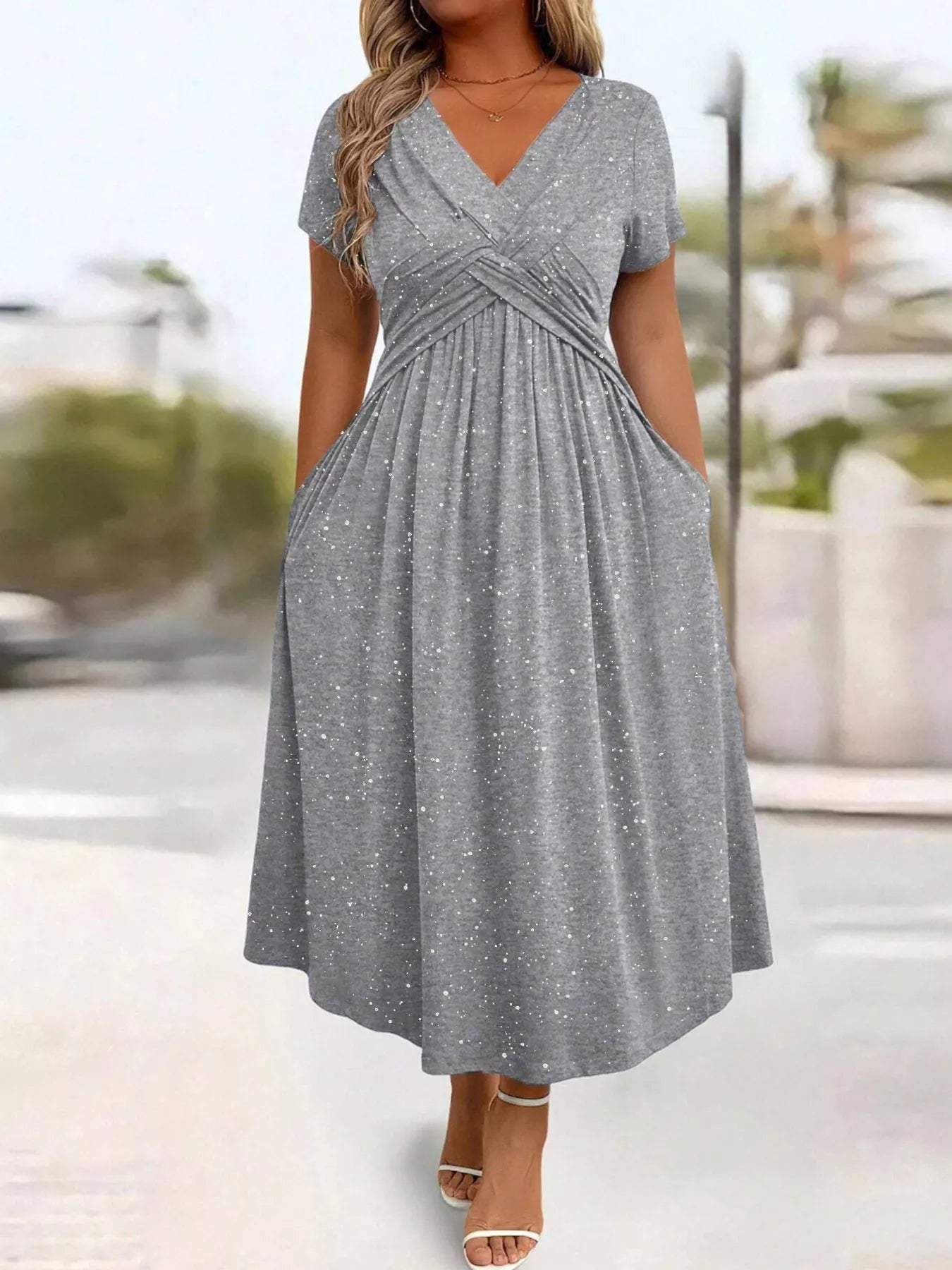 Woman wearing a gray dress with a blurred outdoor background