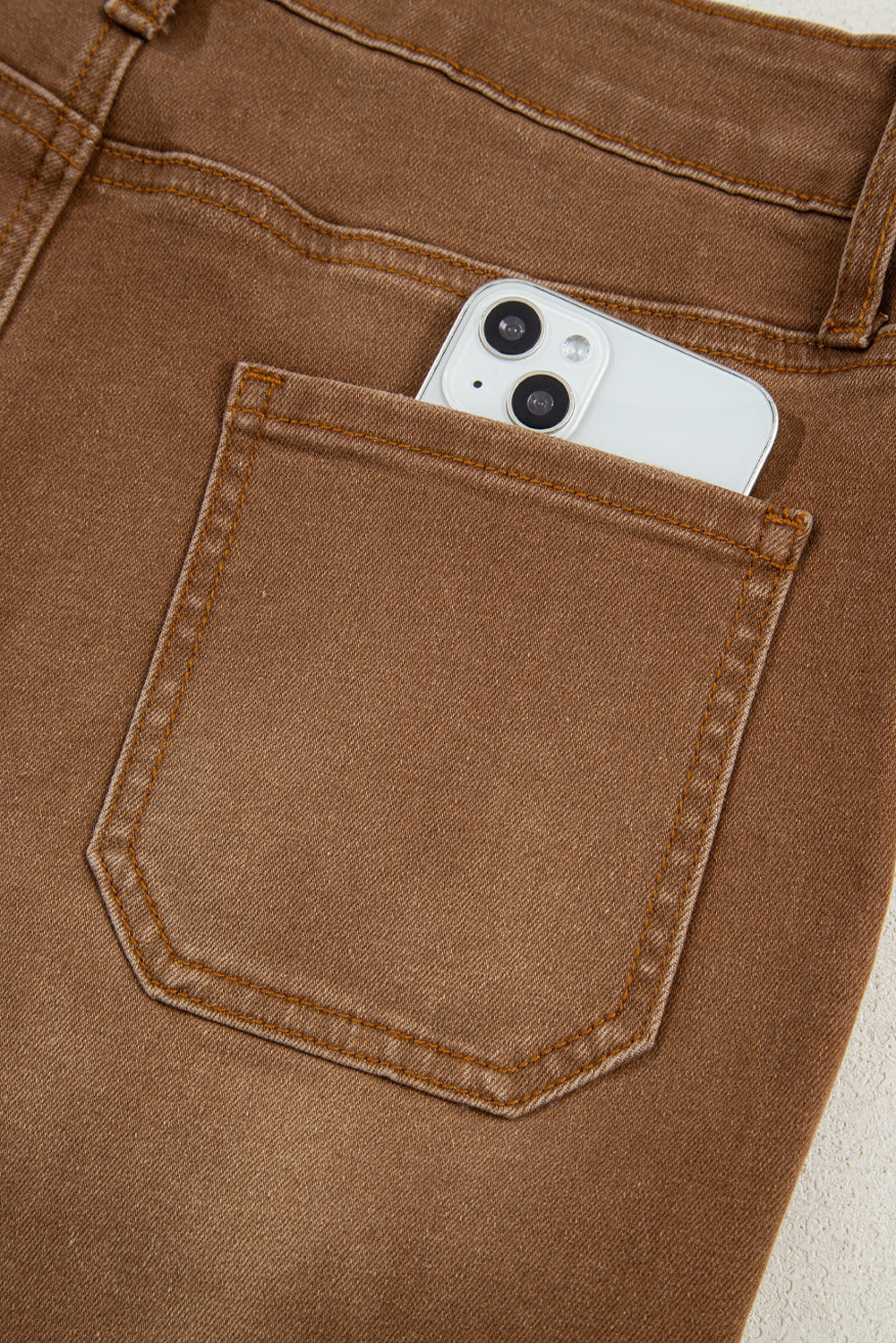 Back view of brown wide leg cropped jeans with a phone in the back pocket.
