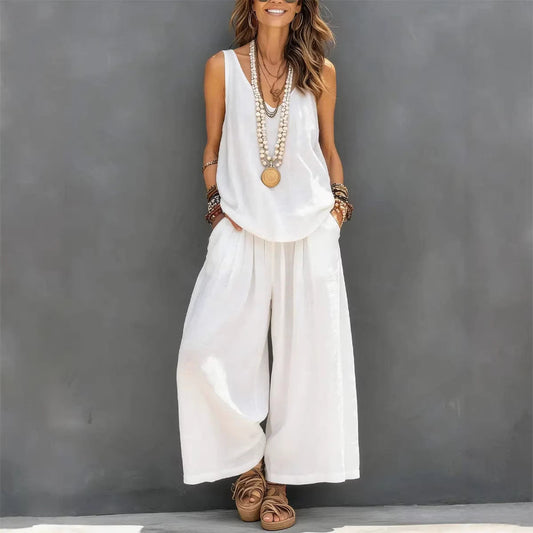 Woman wearing a white sleeveless top and wide-leg pants against a gray background