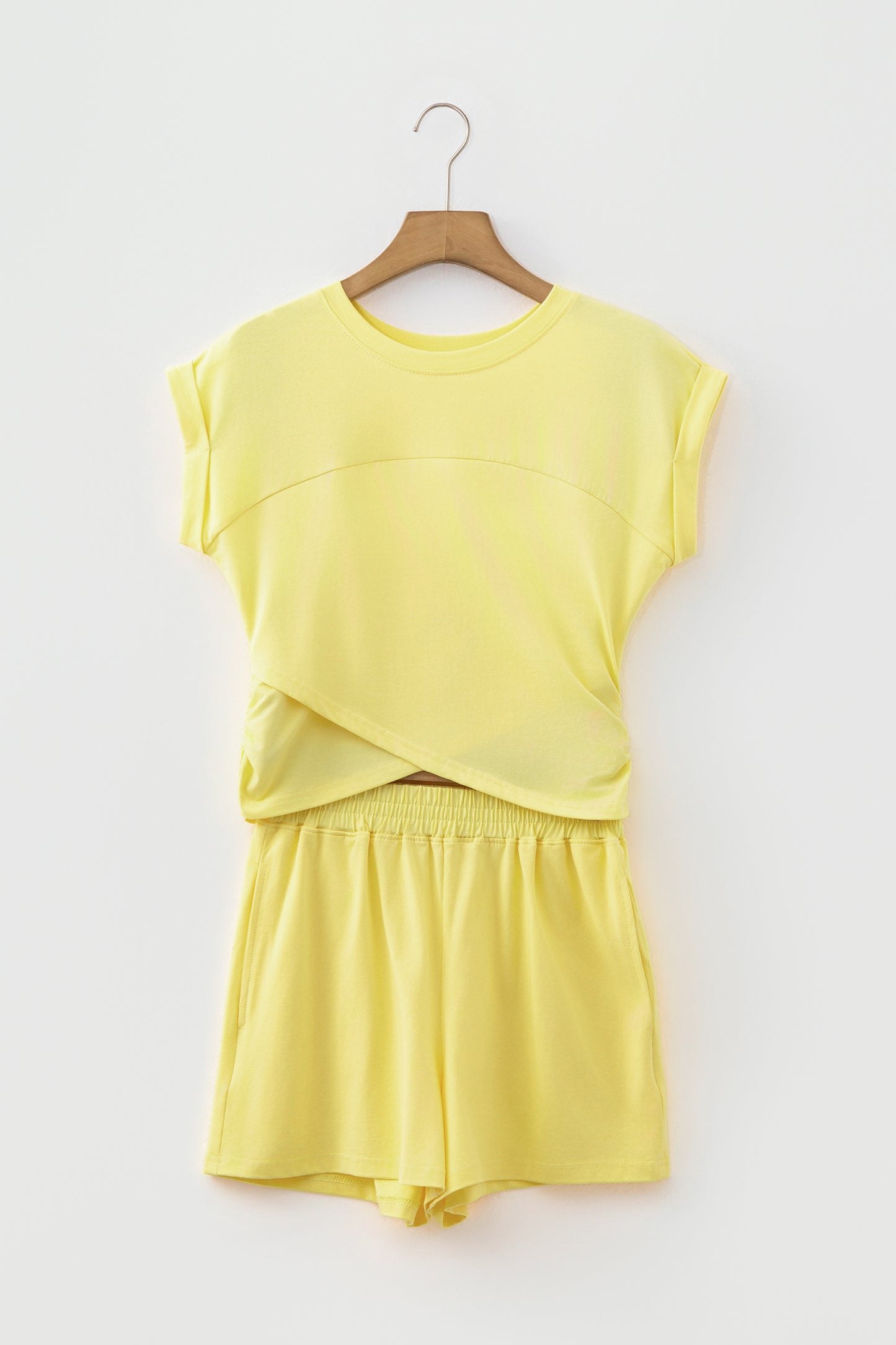 A two-piece yellow lounge set consisting of a short-sleeve top and matching shorts, hanging on a wooden hanger against a light gray background.