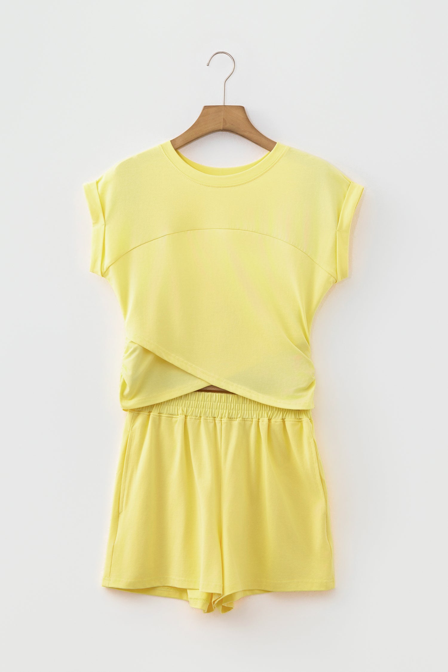 A two-piece yellow lounge set consisting of a short-sleeve top and matching shorts, hanging on a wooden hanger against a light gray background.