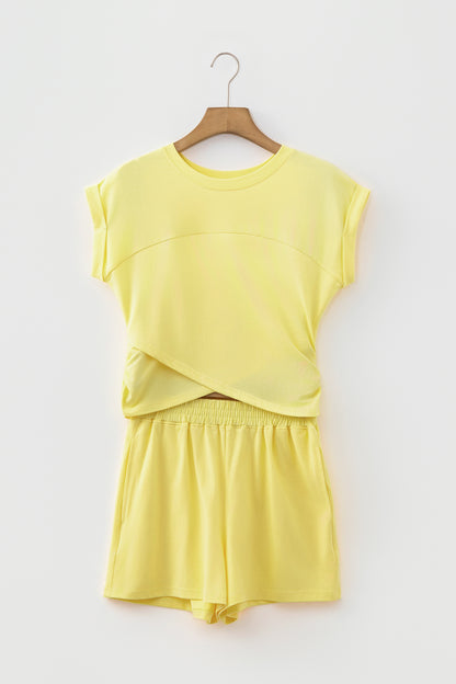 A two-piece yellow lounge set consisting of a short-sleeve top and matching shorts, hanging on a wooden hanger against a light gray background.
