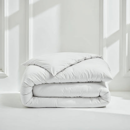 Folded light gray comforter on a white surface with a neutral background