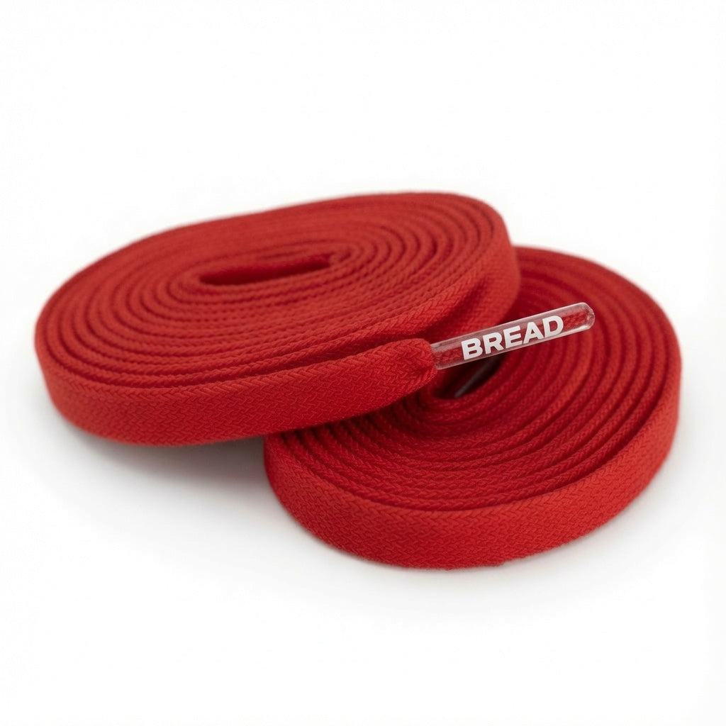 Two coiled red fabric shoelaces with clear plastic tips featuring the white BREAD logo.