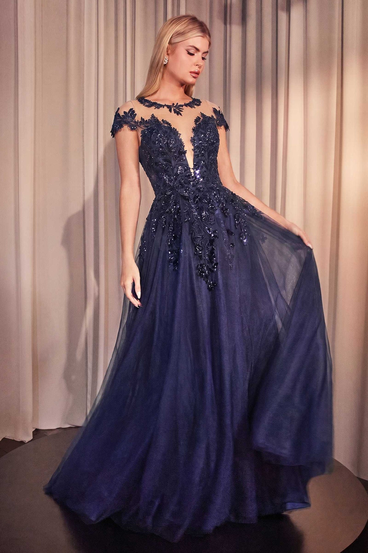 Andrea & Leo A1475 navy blue gown with embellished bodice and cap sleeves, model holding out the tulle skirt.