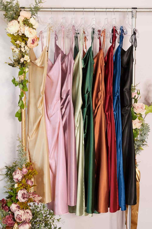 Set of colorful satin dresses on hangers with floral decorations on a white background