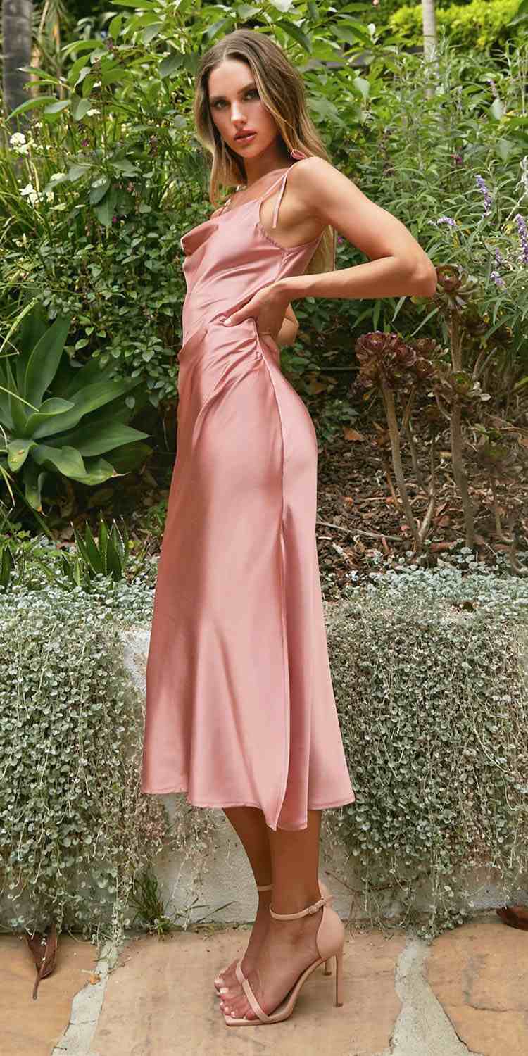 Woman in a pink dress standing in a garden setting