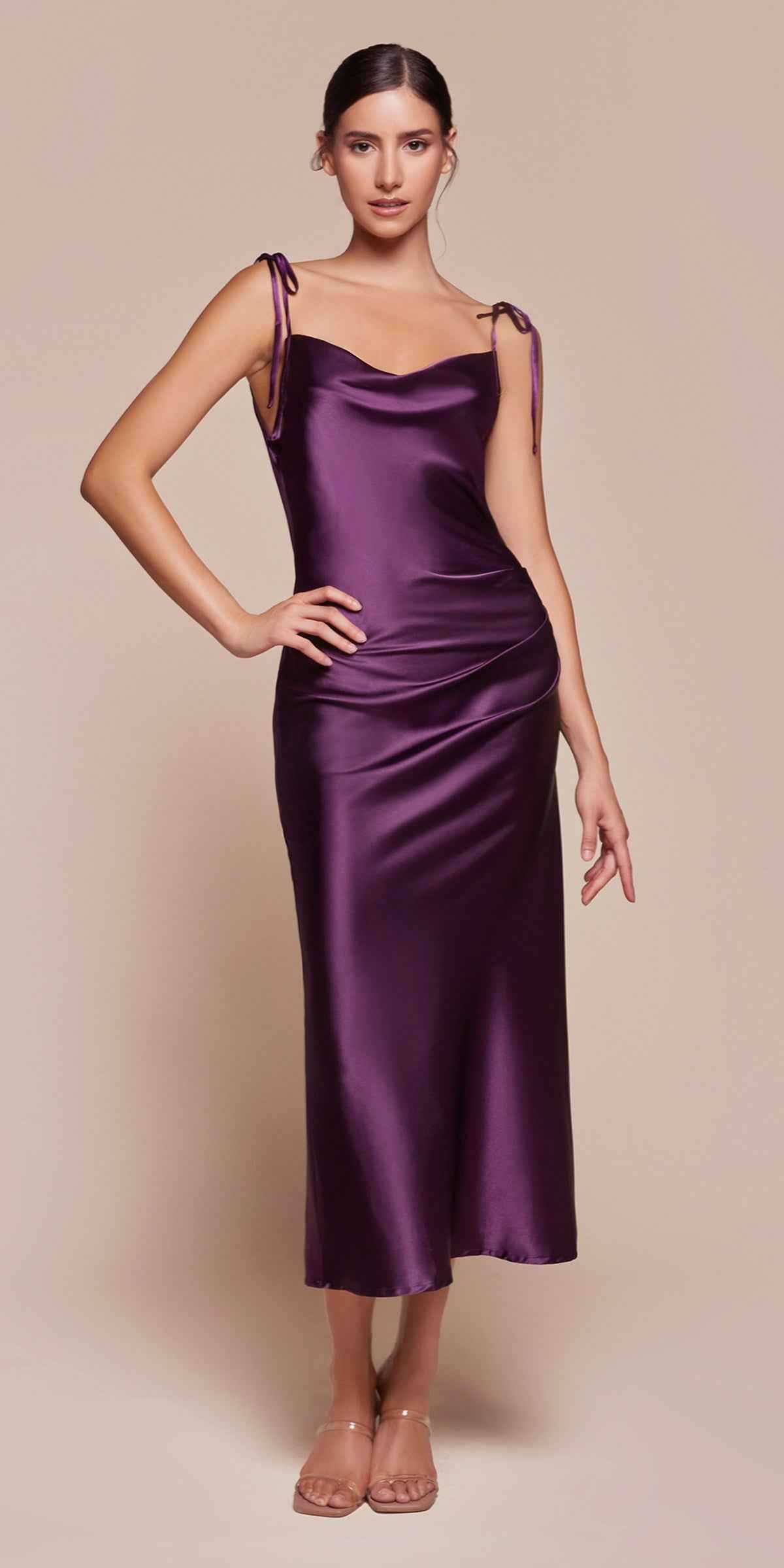 Woman wearing a purple satin dress against a beige background