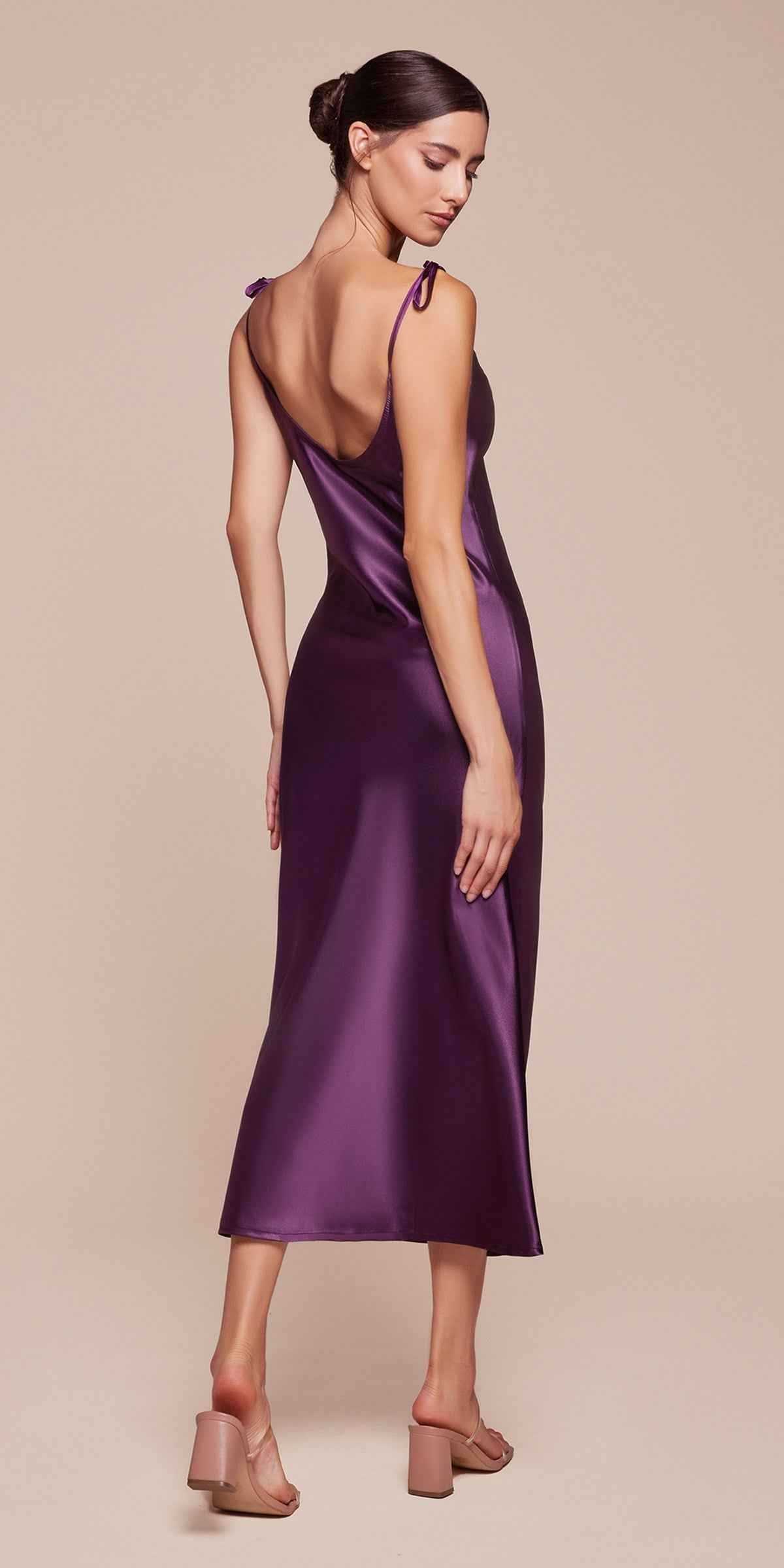 Woman wearing a purple satin dress against a beige background