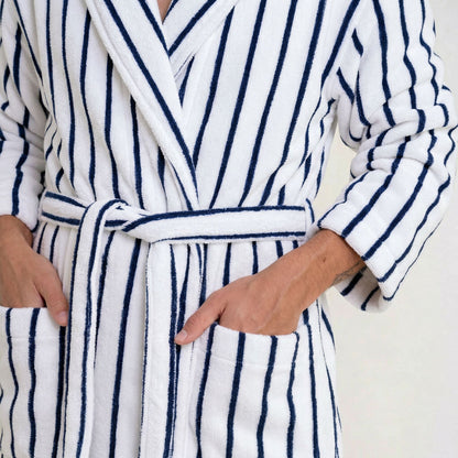 Person wearing a white robe with blue stripes on a plain background