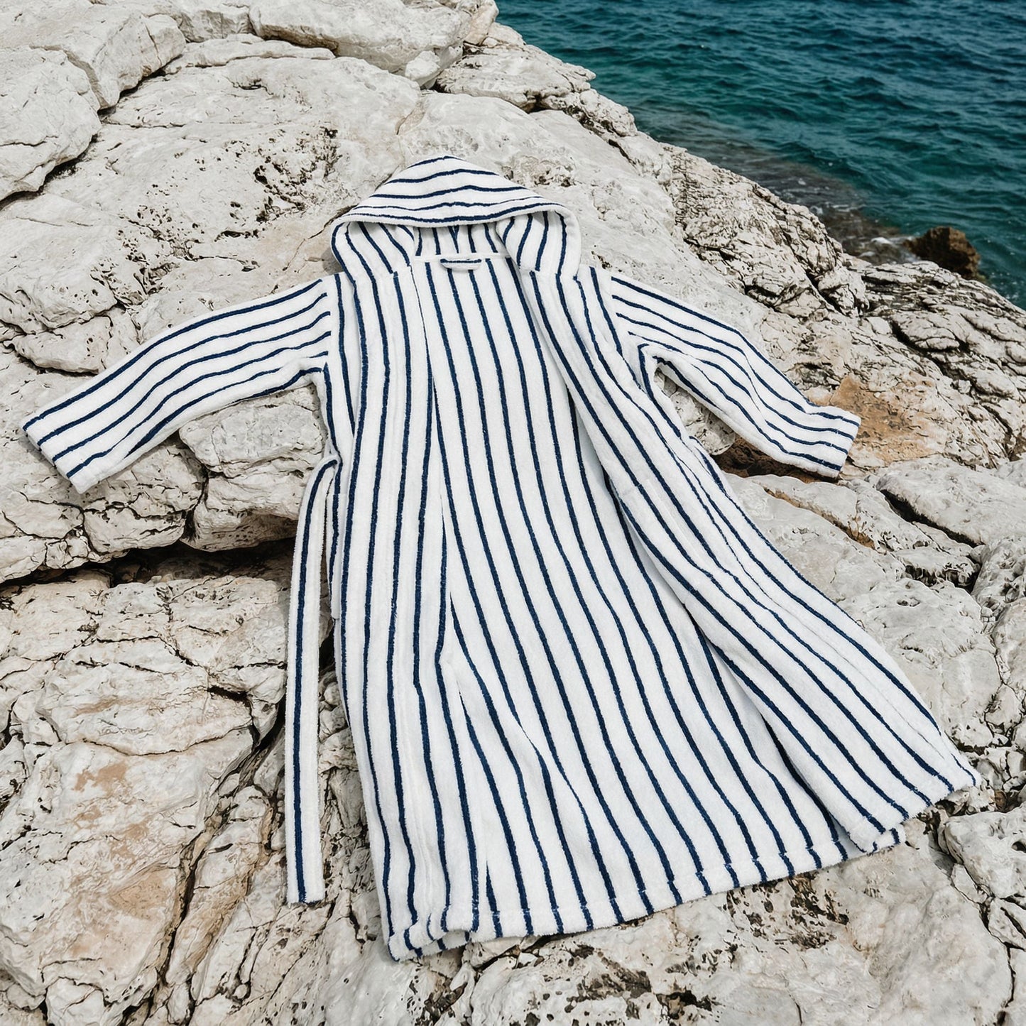 Striped robe on a rocky surface with water in the background