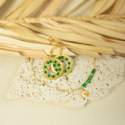 Gold and green beaded earrings on a textured surface with natural light