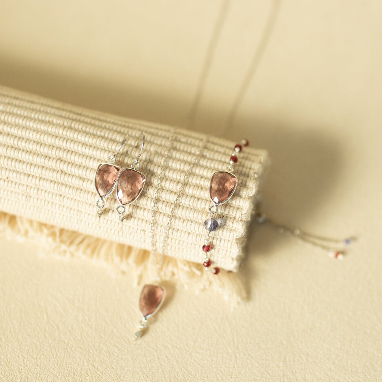 Pair of earrings with heart-shaped stones on a textured beige surface