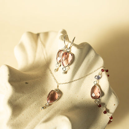 Jewelry set with pink teardrop-shaped stones on a beige background