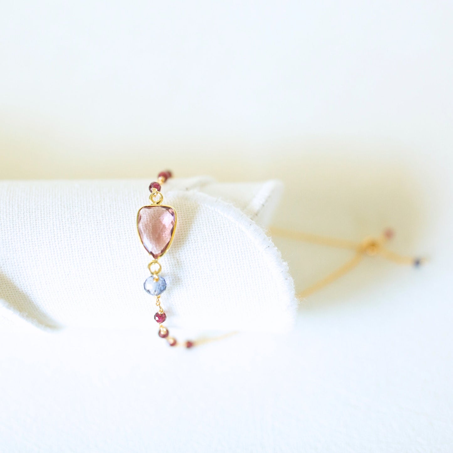 Delicate bracelet with a heart-shaped pink gemstone on a white surface