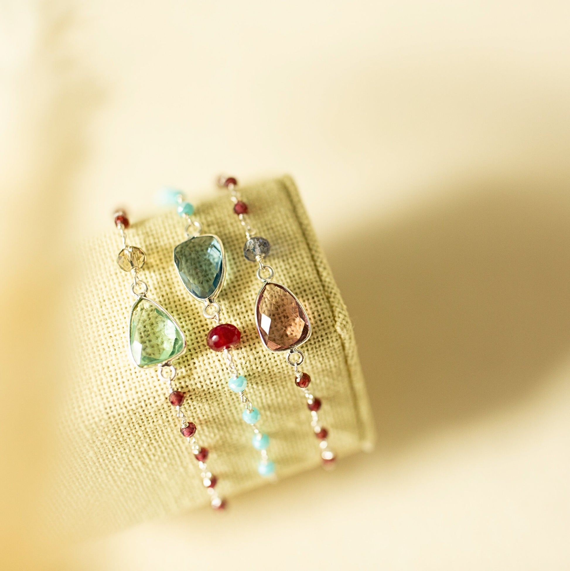 Multicolored teardrop-shaped earrings on a yellow fabric background