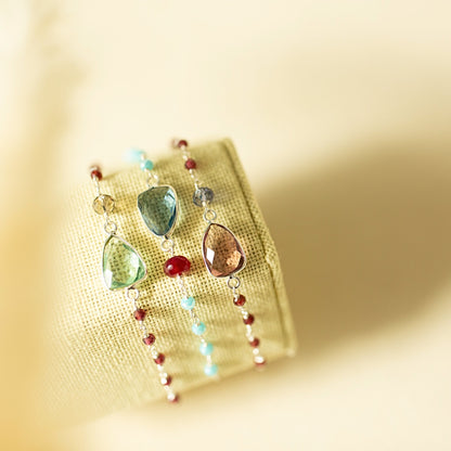 Multicolored teardrop-shaped earrings on a yellow fabric background