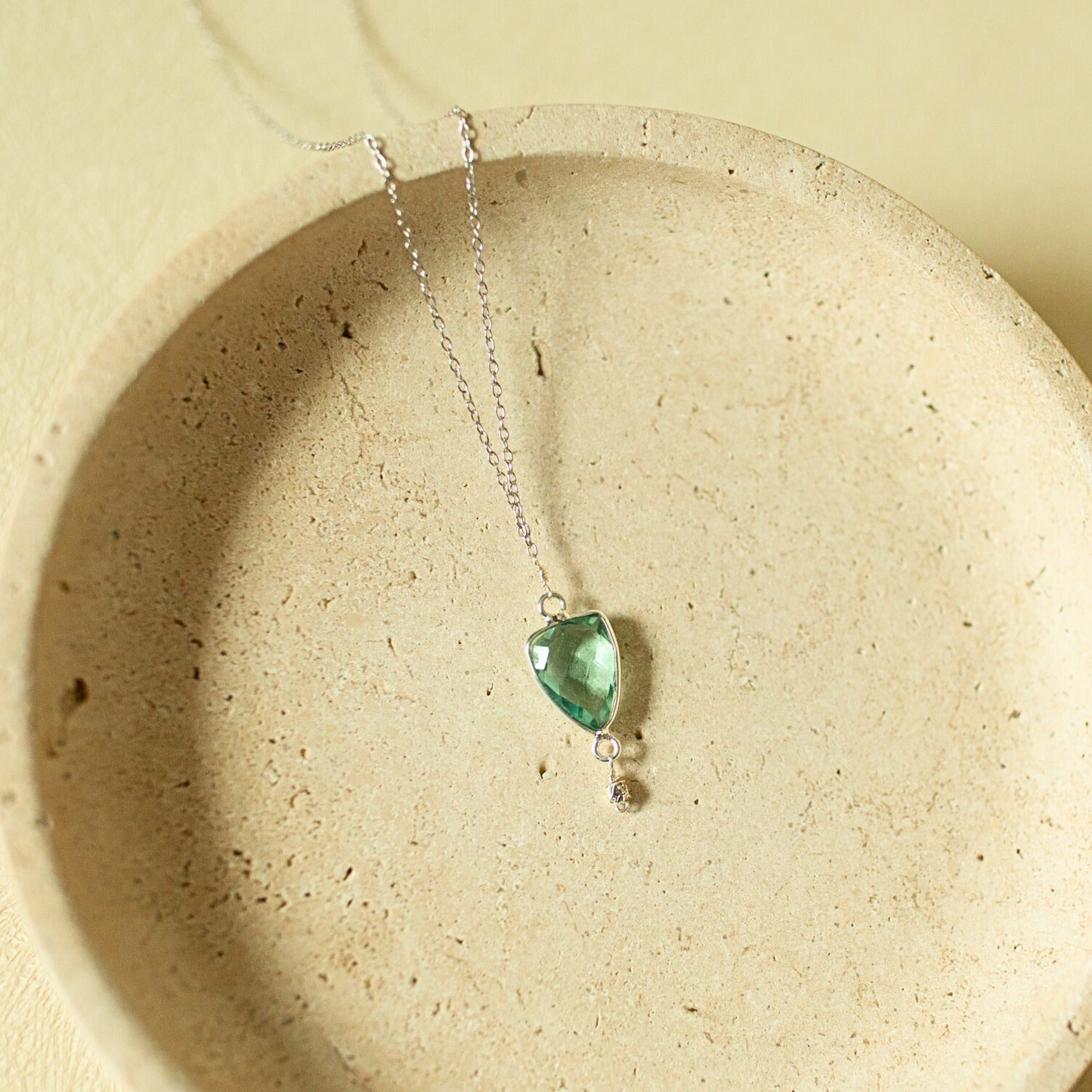 Necklace with a green pendant on a beige surface