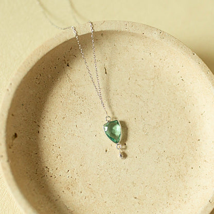 Necklace with a green pendant on a beige surface