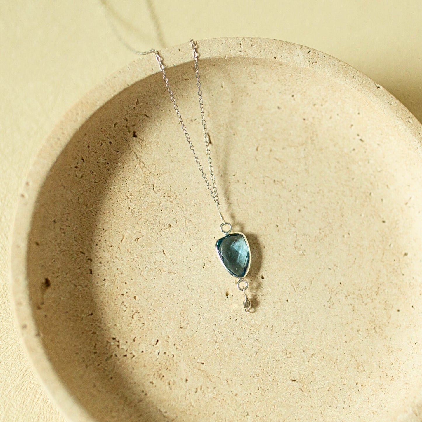 Necklace with a blue pendant on a beige plate