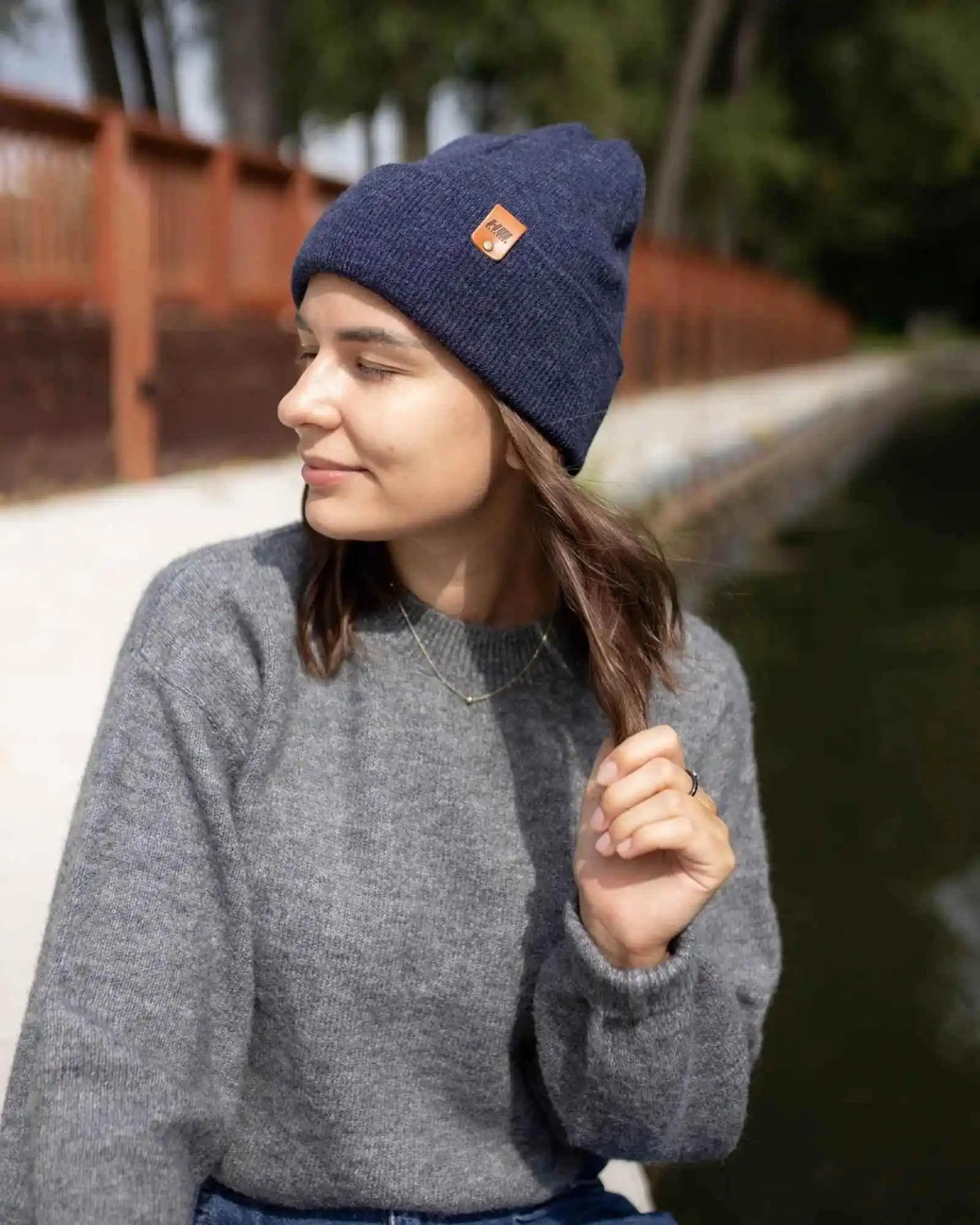 Woman wearing a navy beanie with a brand logo outdoors