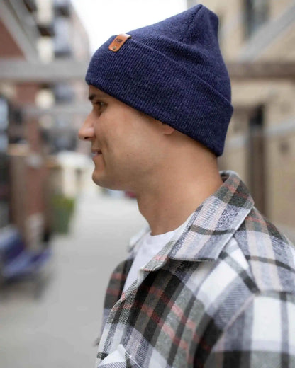 Person wearing a blue beanie and plaid shirt in an urban setting