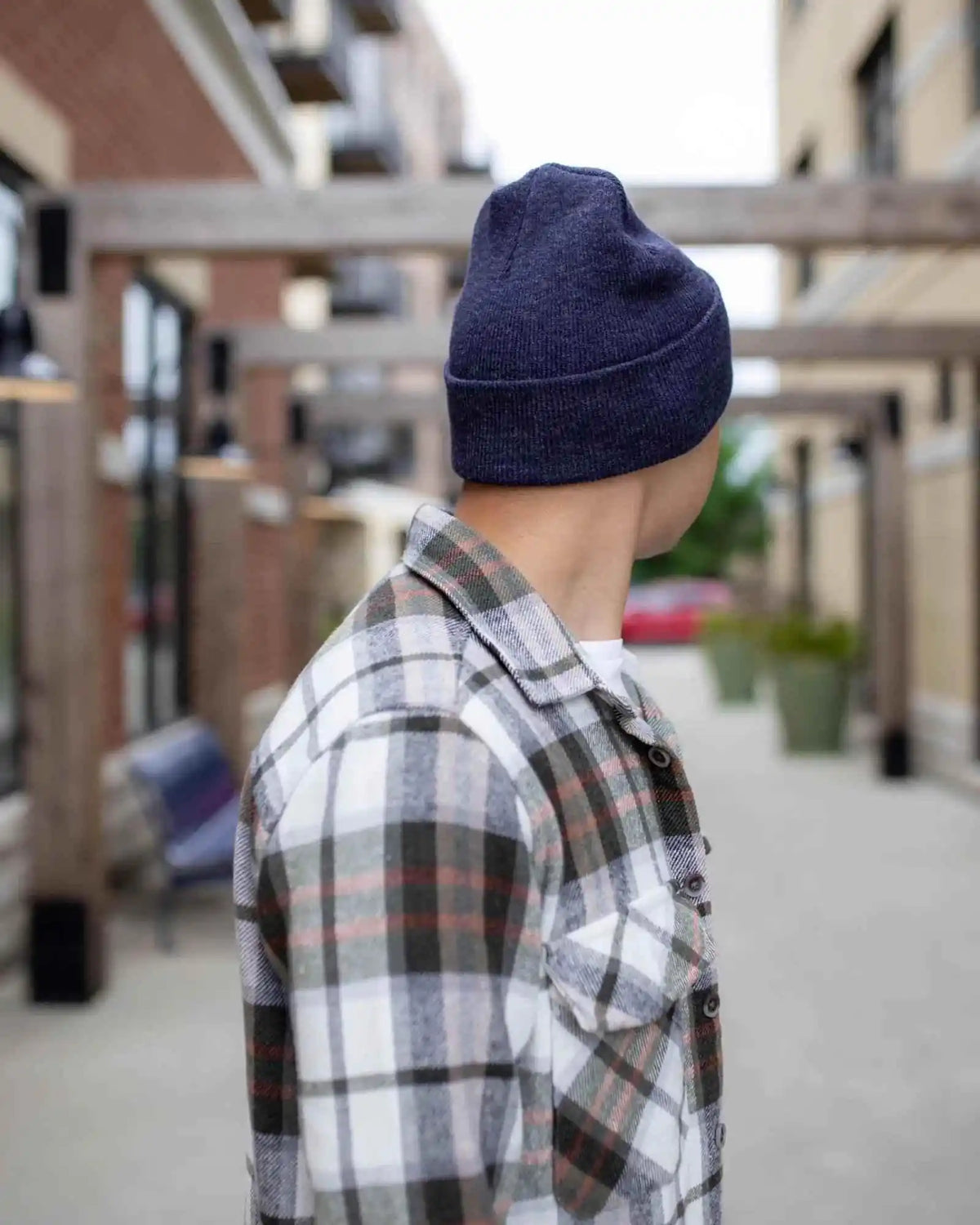 Person wearing a navy beanie and plaid shirt in an indoor setting