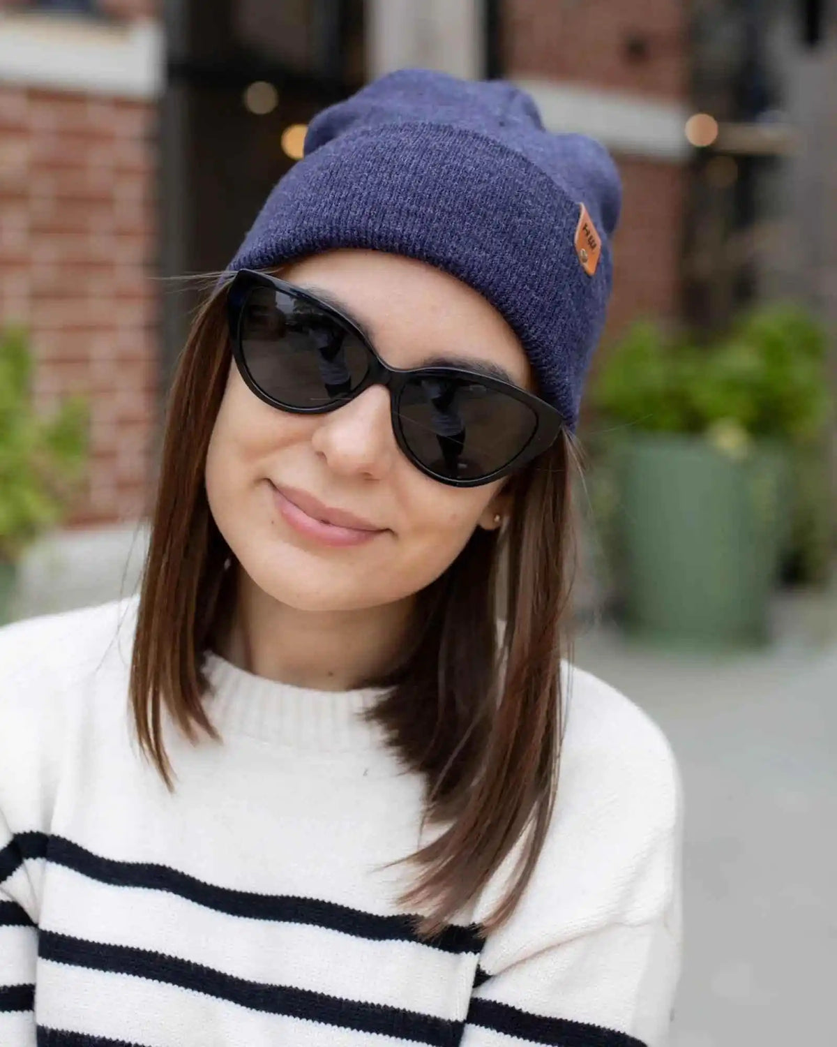 Person wearing a blue beanie and sunglasses with a blurred background
